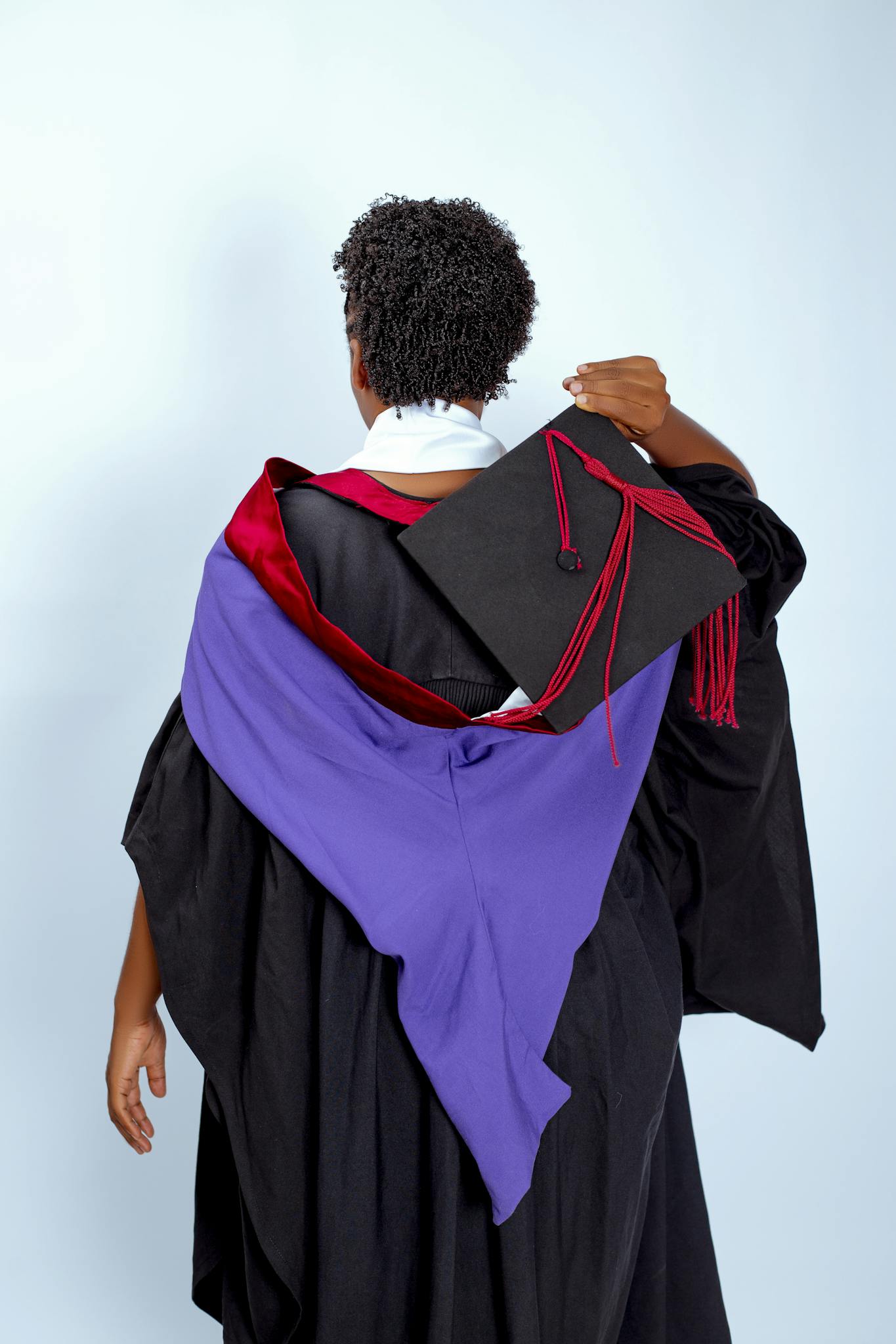 Adult in cap and gown celebrating educational achievement, symbolizing success.